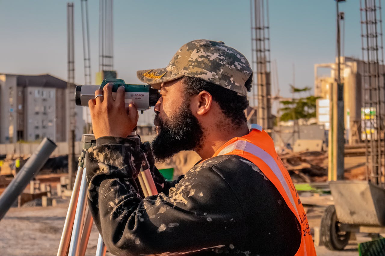 services-04 A construction worker uses a theodolite on a building site, capturing precise measurements.