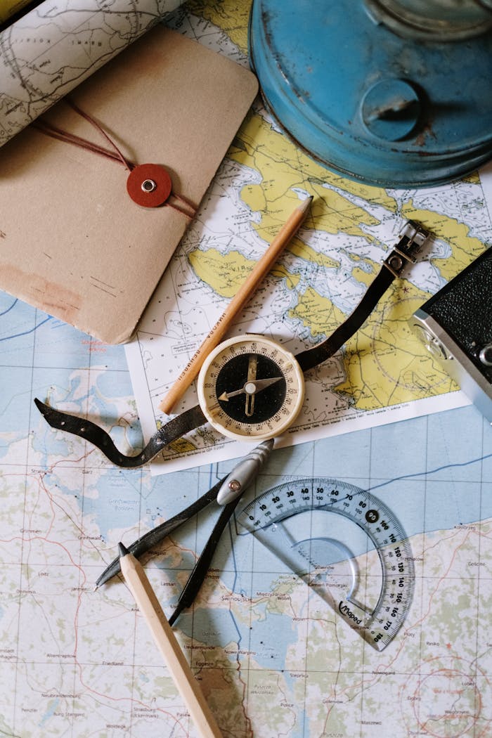 who-we-are Flat lay of vintage compass, protractor, and maps for navigation study.