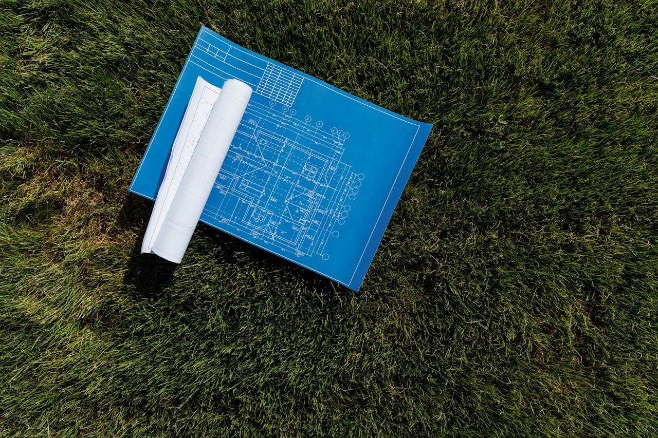 services-04 Top view of architectural blueprints on a grassy field, ideal for construction themes.